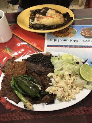 Foreground: carne asada, black beans, pasta salad Background: Tamales