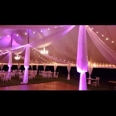 Up lighting, pole drapes, string lights, tables, and chivari chairs.