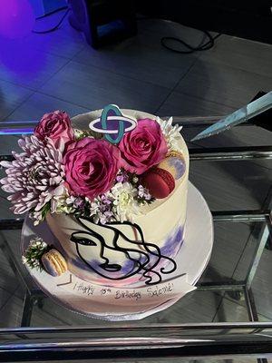 Custom cake from J&D cakes  with TXT album cover art symbol, fresh flowers and macaroons