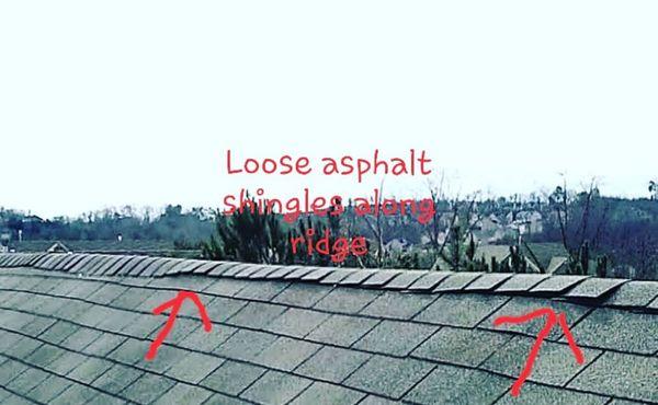 Loose asphalt shingles on roof ridge