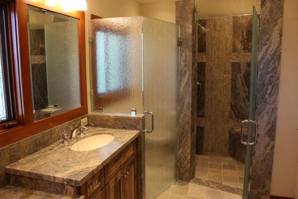 A beautiful remodel done by Nash Construction featuring a spacious, curb-less, marble shower and hickory cabinets with marble slabs.