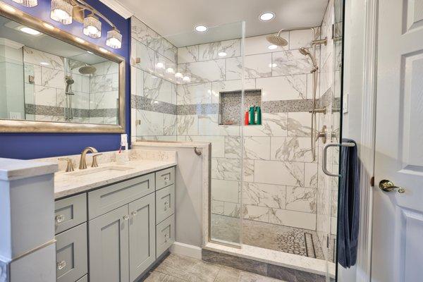 Master bathroom remodel with corner bathtub & marble lined tiles