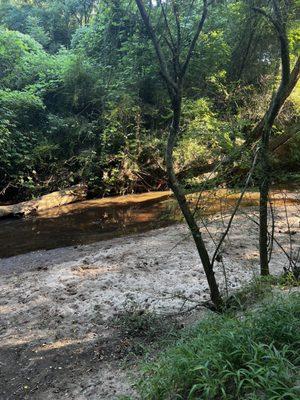 Little stream area with sand. Located behind the field closest to the pool.