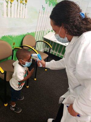 Treatment Coordinator, Diana is checking a patient's temperature upon arrival.