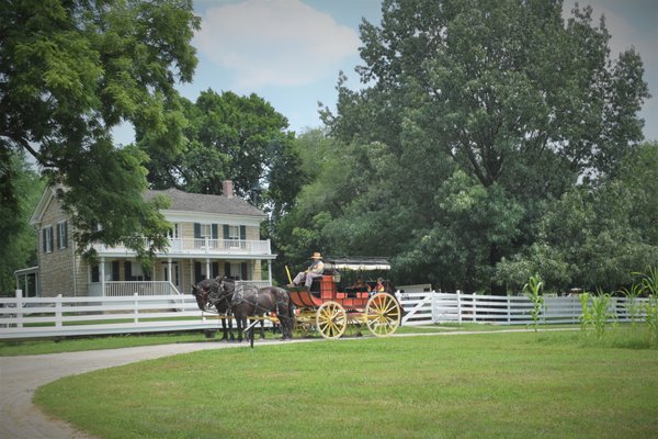 The mudwagon style stagecoach rests in front of the 1865 limestone Mahaffie home.