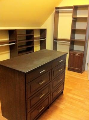 Walk-in Closet in cyanne finish. Including a tilt-out hamper, Island, raised panel doors & adjustable shelving.