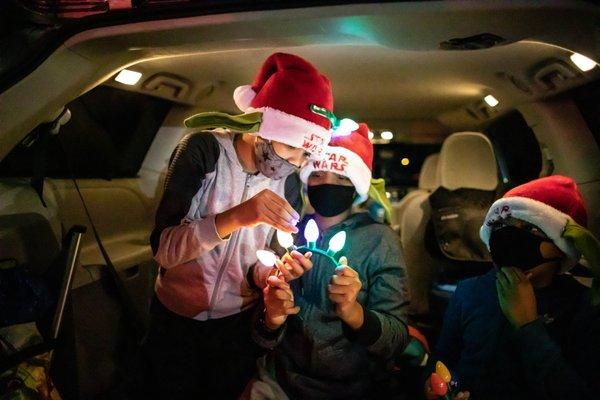 Children playing with Christmas lights in the car at a drive-in movie night.