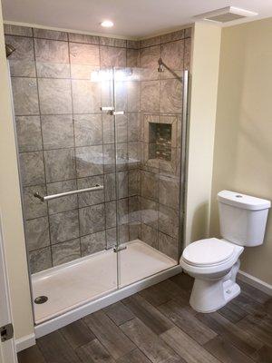 Completed master bathroom in a Canton finished basement.  Ceramic wall & floor tile, solid glass shower doors and custom vanity.