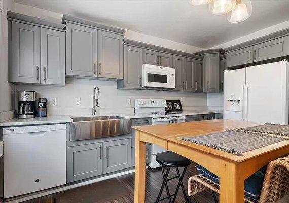 Gray shaker Kitchen cabinet installation done with granite countertop and farm sink.