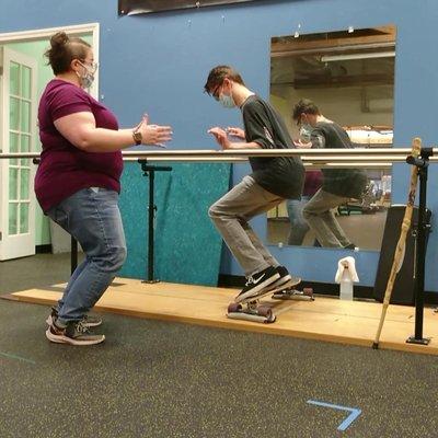 Ashleigh our occupational therapist using a lean board skateboard to work on  stability challenges