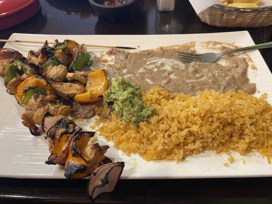 Chicken skewers with red and green peppers and onions, rice, and beans.