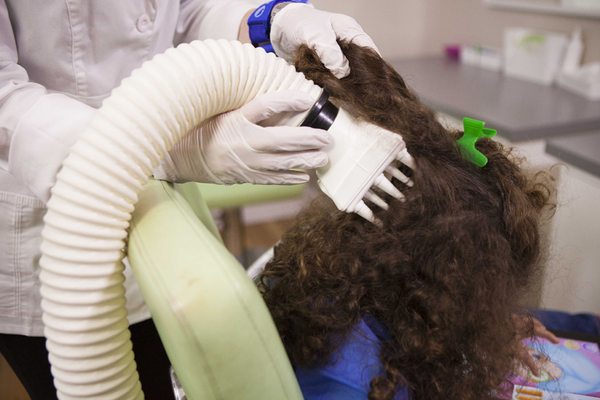 Directing controlled heated air to a child's scalp.