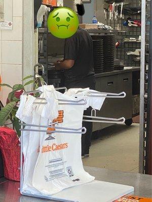 This guy isn't wearing gloves while putting toppings and cheese on pizza.