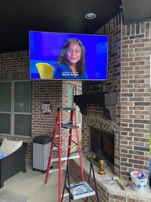 Outside TV mounted on a brick wall.