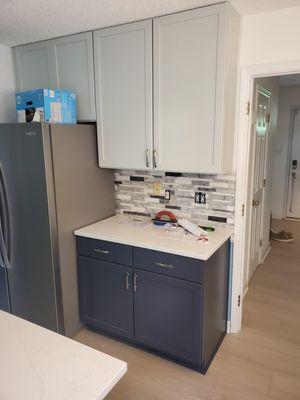 Grey wall cabinets and blue base cabinets completed for remodeling project.