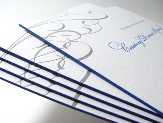 Custom elegant flourish wedding invitation with silver paper backer and two color letterpress print with hand painted edges.