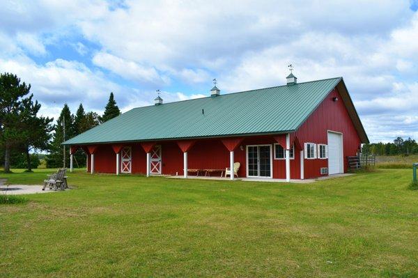 This post frame horse barn by Structural Buildings features a covered porch, decoratice "Y" posts, dutch doors, and cupolas.