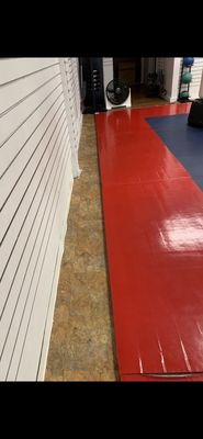 Marble floor next to the training mat. People run bare foot on the red mat surface