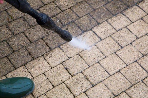 Pressure cleaning concrete pavers to remove moss buildup.