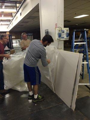 Wrapping hard wall barrier sheet rock panels prior to transport, ICRA 24-hour training.