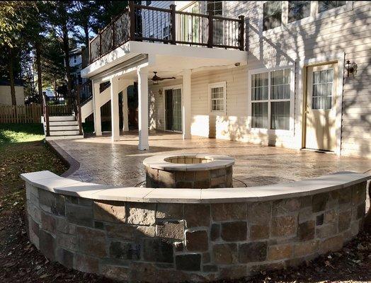 Trex deck and stamped concrete patio with stone wall and fire pit