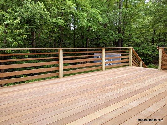 An ipe hardwood deck with horizontal ipe railing installed in a gradient pattern.