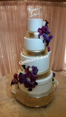 Modern wedding cake gets the gold treatment with this amazing design adorned with a medley of purple flowers.