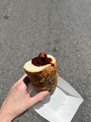 a dollar store hot dog shoved into a chunk of bread with barbecue sauce