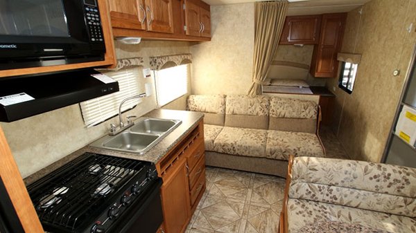 Interior of Starcraft 26' bunkhouse travel trailer. Front queen bed, couch and dining table fold into beds, full kitchen.