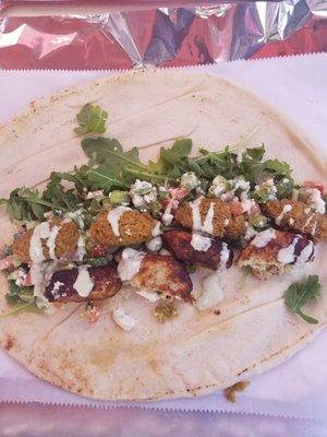 Chicken Kufta wrap with arugula, falafel, tomatoes, feta cheese + scallions