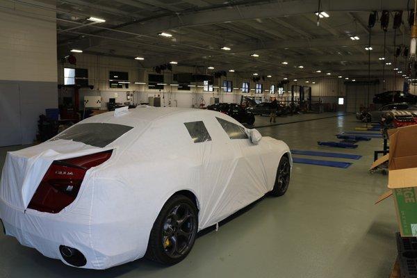 There's a 2018 Giulia Quadrifoglio nestled beneath its shipping blanket in the Leith Alfa Romeo of Raleigh Service Bay.