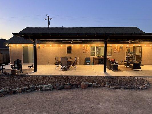 Backyard view of patio cover with lights on