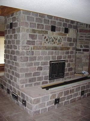 Custom built granite masonry heater with heated bench and oven