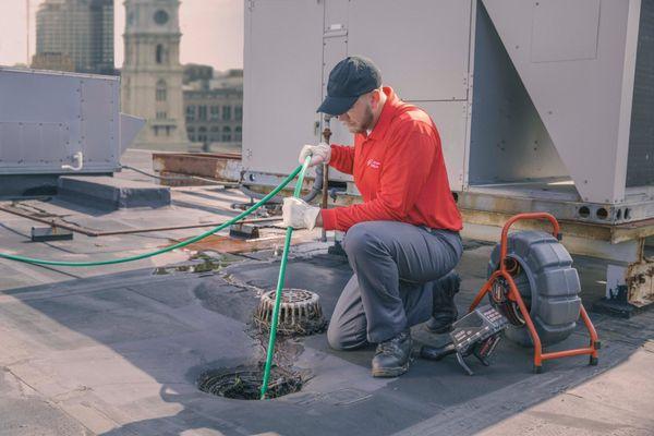 Technician power jetting stack lines from from a roof of commercial building. Stack, Jet, Snake, Roof, Drains, Emergency