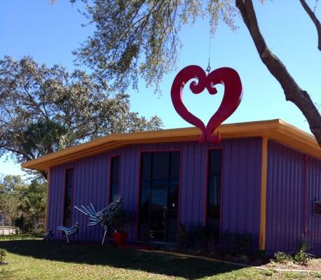 Front of Rustic Steel Creations shop with metal heart hanging from a tree.