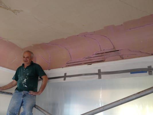 Victor on the scaffold after opening up the damaged plaster coved ceiling (the pink is an adhesive applied to bond new plaster)