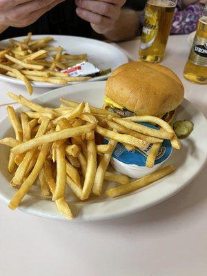 Cheeseburger and a side of fries. Burger comes naked with pickles on the side. Ketchup and mustard at the table.