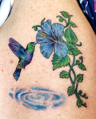 Hummingbird tattoo on outer arm.