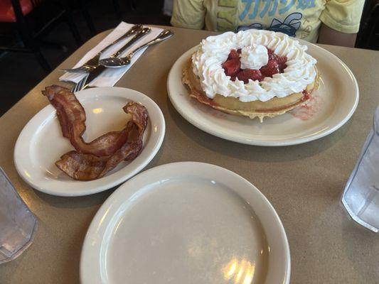 Belgian Waffle with Strawberries and Whipped Cream, served with bacon.