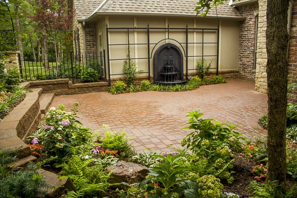 An impressive courtyard with wrought-iron accents, a trellis, a water fountain, and a luscious shade garden in Oklahoma City.