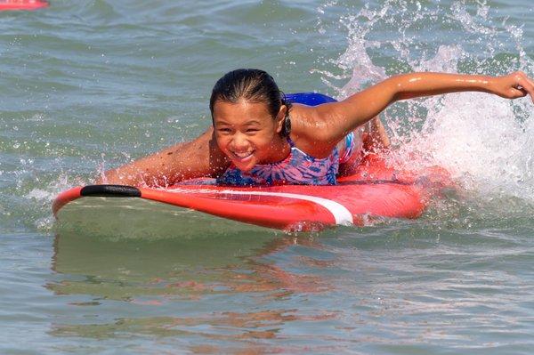 Paddling out on a surfboard at kids' beach camp