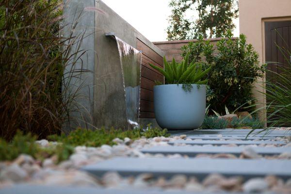 This former project features a modern paving design, statement planters, and a custom water feature.