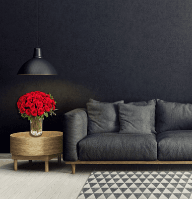 A striking room with sleek black walls, where a beautiful arrangement of red roses vividly stands out, adding warmth and color.