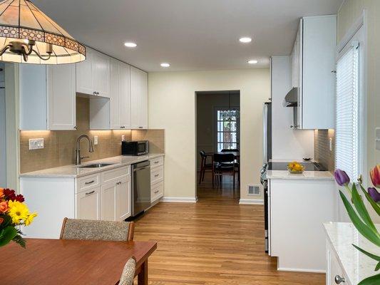 White modern Kitchen with hardwood floor, undercabinet lighting and quartz countertop. design and installed by Aladdin Carpet and Floors