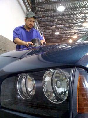 Professional Detailer adding a layer of wax on a vehicle.