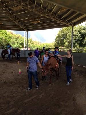 The kids riding in the arena. 3 spotters for every child.