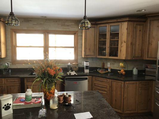 Cutout the drywall around cabinets & countertops & replaced with concrete boards & installed stone on the walls