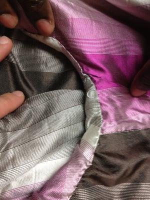 Closeup of poor stitching where sleeve meets coat body.