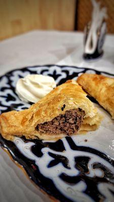 Meat Pirozhki - Baked pies made with filo dough, stuffed with ground beef and onions seasoned with spices, served with sour cream.