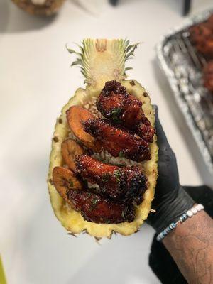 Honey jerk wings, rice & peas, sweet plantains in a pineapple bowl.